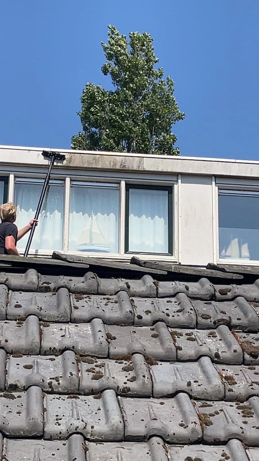 Medewerker van De Haan reinigt ramen op hoogte vanaf het dak